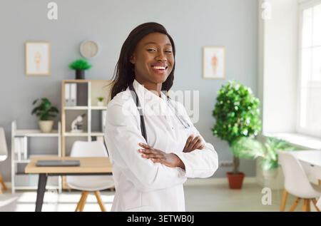 Portrait of a young female doctor in white medical uniform standing in her office. Stock Photo