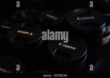 Lviv, Ukraine - June 21, 2026: Group of professional Canon camera lenses with protective caps on dark background close up Stock Photo