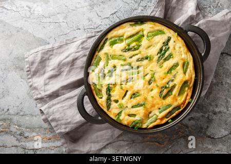 Keto diet asparagus frittata mea closeup in the skillet on the table. Horizontal top view from above Stock Photo