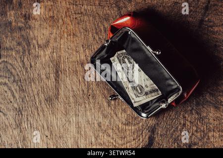 One US dollar bill inside open red vintage purse. Single crumpled one dollar banknote in a small retro wallet. Conceptual image for poverty, financial Stock Photo