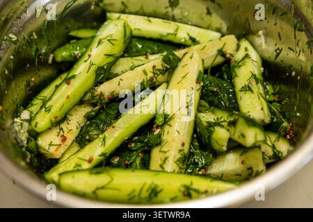 Homemade quick pickled cucumber spears coated with dill, garlic and mustard, ready to marinate in a bowl for fresh crunchy flavor! Yum!!! Stock Photo