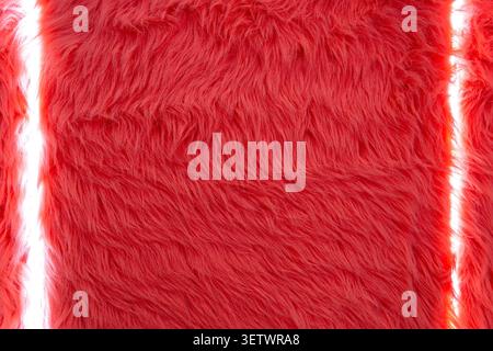 Vivid red faux fur texture close-up. Close-up of vivid red faux fur with dense shaggy fibers, soft plush texture, and narrow vertical white light gaps Stock Photo