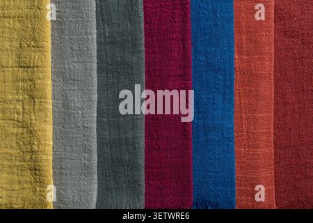 Colorful textured cotton fabric swatches background. Flat lay of various crinkled cotton or linen fabric samples arranged in stripes showing rich text Stock Photo