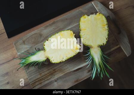 Fresh pineapple cut in half on a wooden cutting board ready for nutrition analysis in a bright kitchen setting Stock Photo