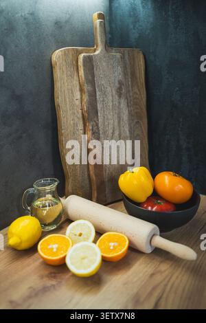 Colorful fruits and vegetables on a wooden table in a kitchen setting with a cutting board Stock Photo