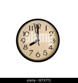 A round classic wall clock with a beige face and black numbers shows almost eight o'clock against a white background. Stock Photo