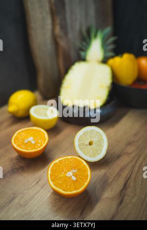 Display of assorted fruits like oranges, lemons, and pineapples on a wooden surface in a nutritionology setting Stock Photo