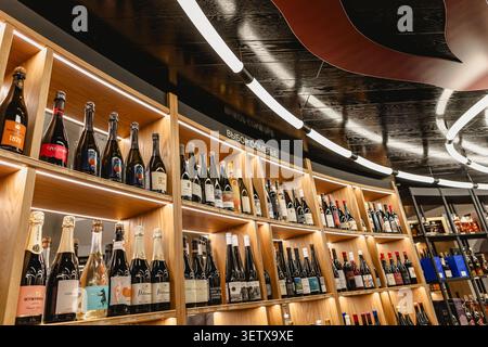 Gelendzhik, Russia - June 14, 2026: Opening of the White Cape wine city. Modern wine store interior with curved wooden shelves showcasing rows of wine Stock Photo