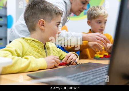 Students focusing on building and programming robots with a teacher's guidance Stock Photo
