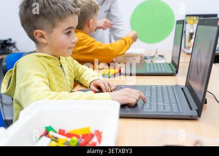 Student focusing on coding on a laptop in a classroom during a robotics workshop Stock Photo