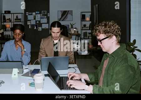 Diverse Coworkers Working on Laptops in Modern Office Team Meeting Stock Photo