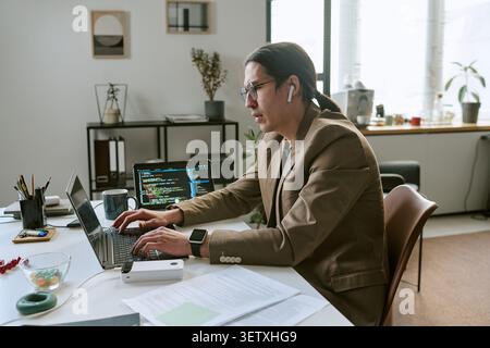 Asian Man Coding on Laptop in Office  Stock Photo