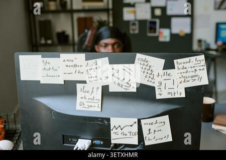 Adult Man Coding Behind Monitor Covered with Workflow Notes Stock Photo