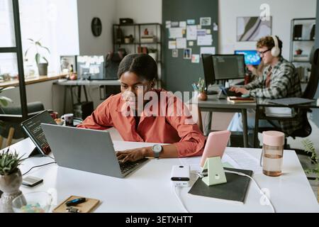 Black Woman Developer Working on Laptop in Modern Office Stock Photo