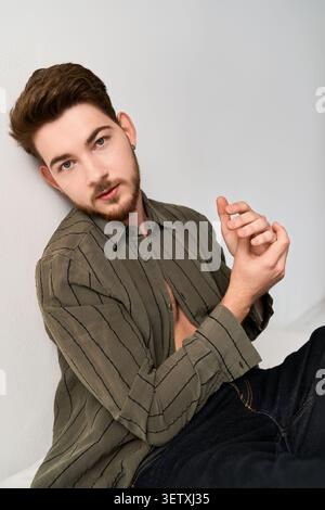 Charming young man with a beard poses effortlessly, highlighting modern casual style Stock Photo