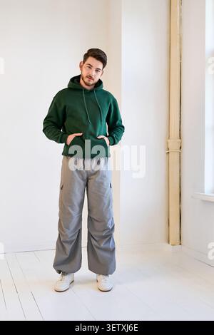 Confident young man with a beard poses in stylish casual wear in a bright studio Stock Photo