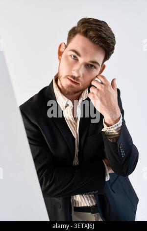 Young man with a beard poses confidently in a fashion-forward studio, embracing style Stock Photo