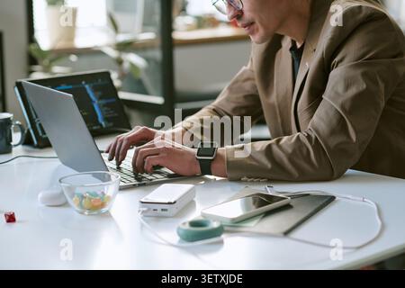 Adult Man Typing on Laptop in Modern Remote Work Setting Stock Photo