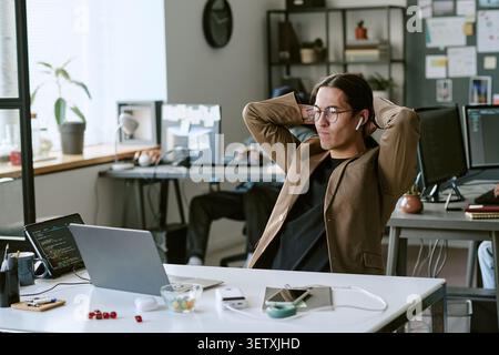 Adult Man Relaxing at Desk during Work Break in Modern Office Stock Photo
