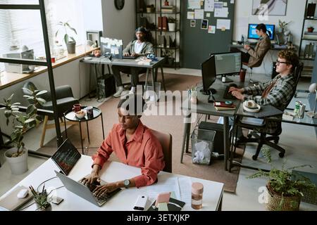 Black Woman Working on Laptop in Modern Collaborative Office Stock Photo