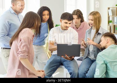 Teacher and students collaborate on laptop during group project in classroom Stock Photo