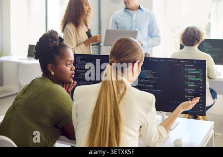 Developers collaborating on code review and mentoring in a modern tech office Stock Photo