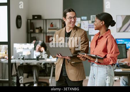Black Woman and Man Collaborating with Laptop in Office Stock Photo