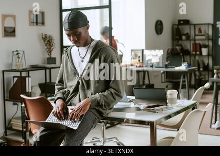 Black Man Working on Laptop in Modern Shared Office Stock Photo