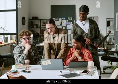 Diverse Business Team Collaborating on Laptop in Modern Office Stock Photo