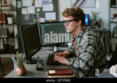 Adult Man Coding at Dual Monitors in Software Development Office Stock Photo