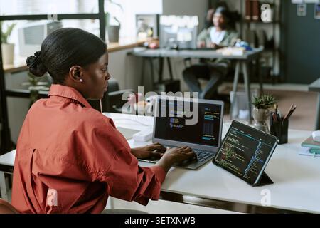 Black Woman Developer Coding on Laptop in Modern Office Stock Photo