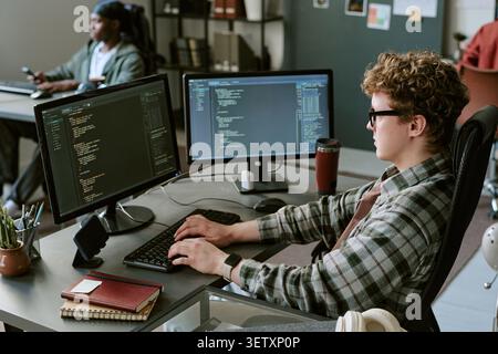 Caucasian Man Programming at Dual Monitors in Startup Office Stock Photo