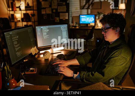 Adult Man Coding at Dual Monitors in Office at Night Stock Photo
