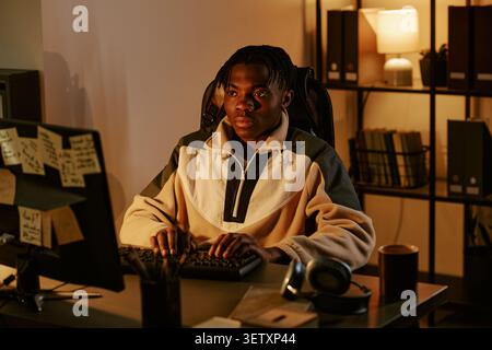Black Man Working on Computer in Office at Night Stock Photo