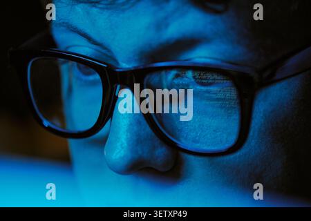 Adult Man Wearing Glasses Monitoring Code on Screen at Night Stock Photo