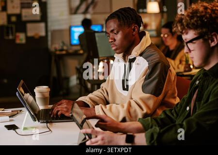 Black Man Working on Laptop in Collaborative Startup Office Stock Photo