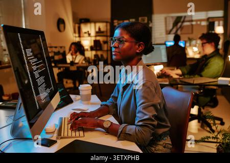 Black Woman Developer Coding at Computer in Modern Office Stock Photo