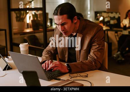Asian Man Working Late on Laptop in Office under Stress Stock Photo
