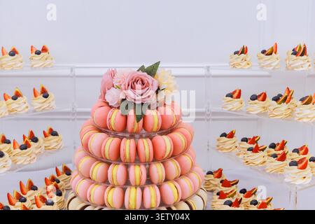 Colorful macarons, decorated cupcakes is set up on table for guests to enjoy at gathering. Stock Photo