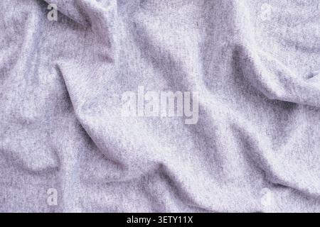 Top view full frame background of a crumpled soft gray knit fabric texture, showcasing gentle folds and wavy creases on a cozy warm cotton material su Stock Photo