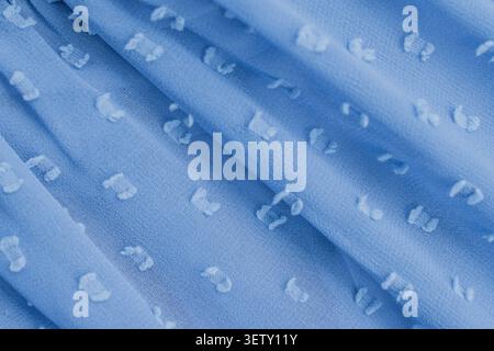 Top view full frame background of a soft blue chiffon fabric texture with white tufted dots, showcasing elegant diagonal folds on a delicate airy mate Stock Photo