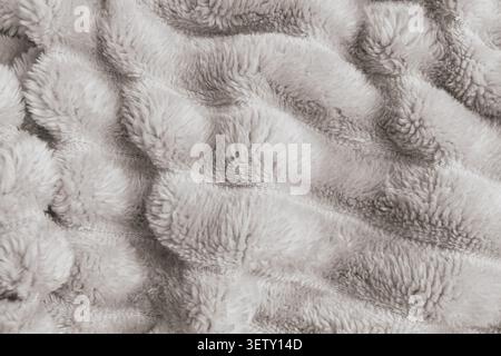 Top view full frame background of a plush wavy faux fur fabric texture, showcasing soft fluffy ridges and cozy fleece lines on a warm blanket blanket Stock Photo
