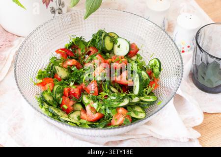A bowl filled with a salad of sliced tomatoes and cucumbers mixed with onions, dill, and parsley is ready to be served. Ingredients are fresh from loc Stock Photo