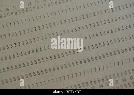Macro close-up of vintage computer punch card with printed numerical data rows, retro technology concept, obsolete data storage media texture. Stock Photo