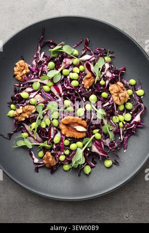 Tasty salad with red cabbage, walnuts, green peas and microgreens on grey table, top view Stock Photo