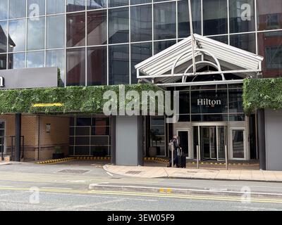 Exterior entrance of a Hilton hotel with glass facade and revolving doors. Leeds, UK. Stock Photo