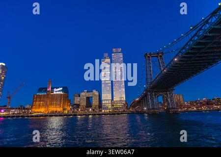 New York City, USA – April 12, 2026: Evening view of the Manhattan Bridge spanning the East River with illuminated Brooklyn waterfront buildings and c Stock Photo