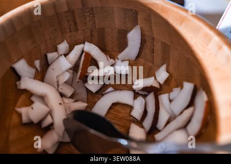 Fresh coconut pieces in a wooden bowl with metal tongs, Maldives Stock Photo