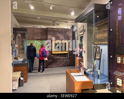 Visitors observing historical displays inside Leeds City Museum, West Yorkshire, England, featuring collections, glass cabinets, and art. Stock Photo