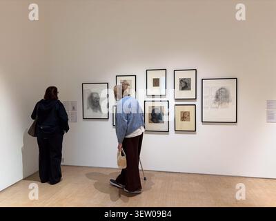 Two women viewing framed figurative charcoal sketches on a white wall in Leeds Art Gallery, Leeds, West Yorkshire, England. Stock Photo
